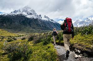 two people hiking toward snowy peak