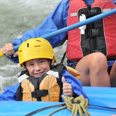 Boy making thumbs up sign in raft