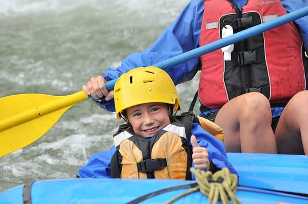 Boy making thumbs up sign in raft