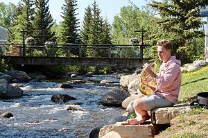 Man sitting by river playing instrument