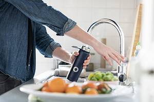 woman filling up reusable water bottle 