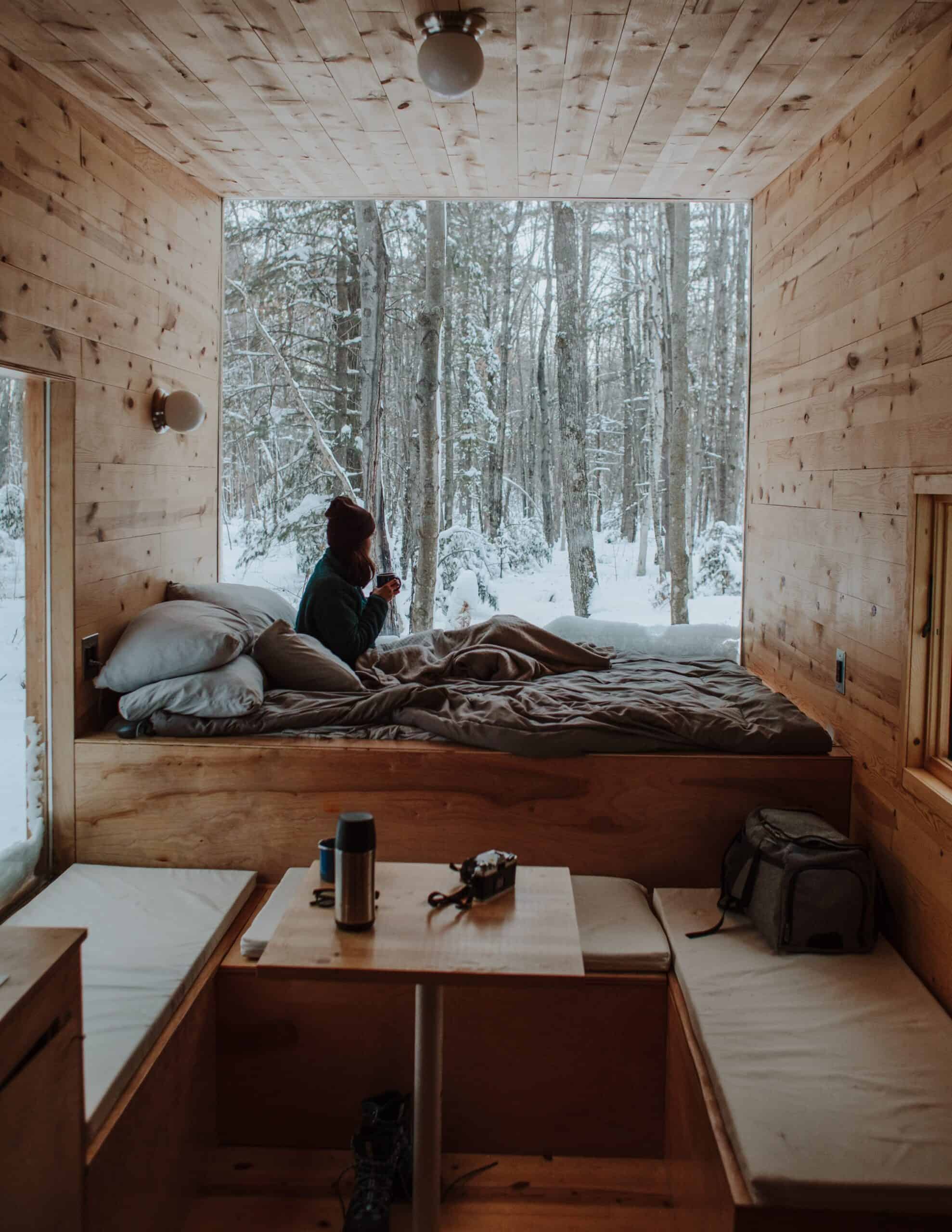 woman cozy in bed with snowy trees out window